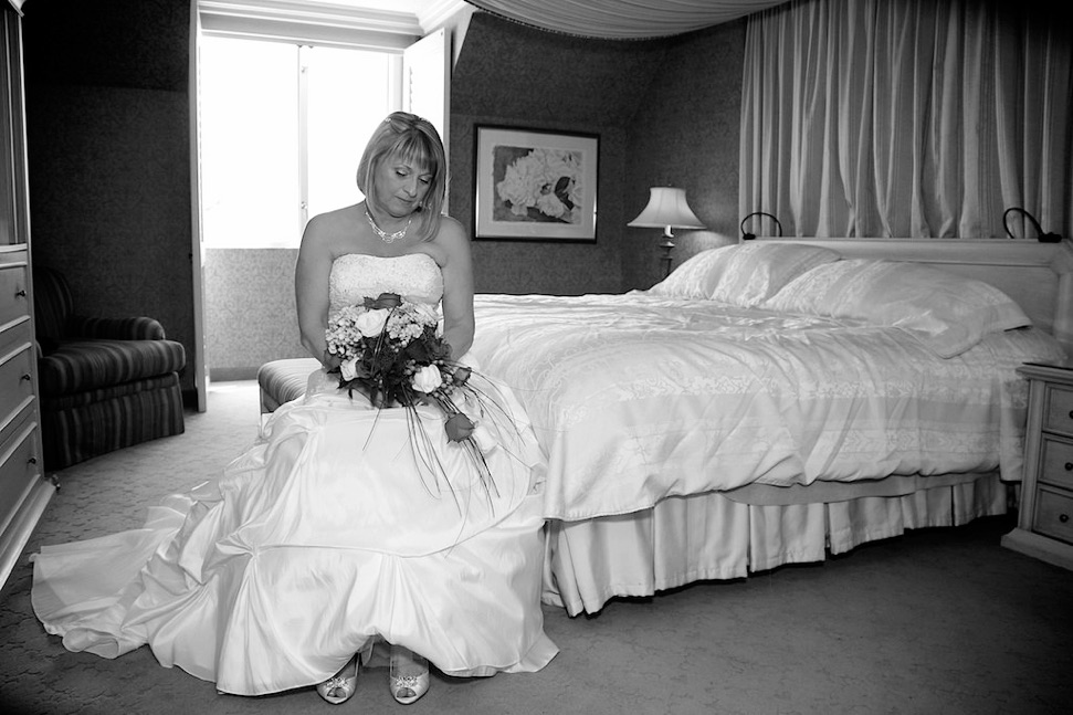 la mariiée assie sur le lit et regarde le bouquet