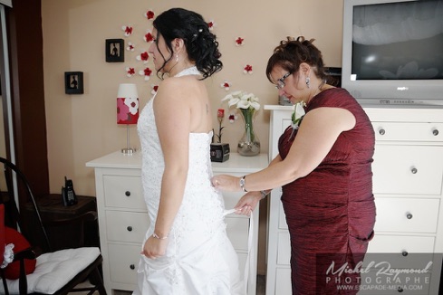 la mère attache la robe de la futur mariée